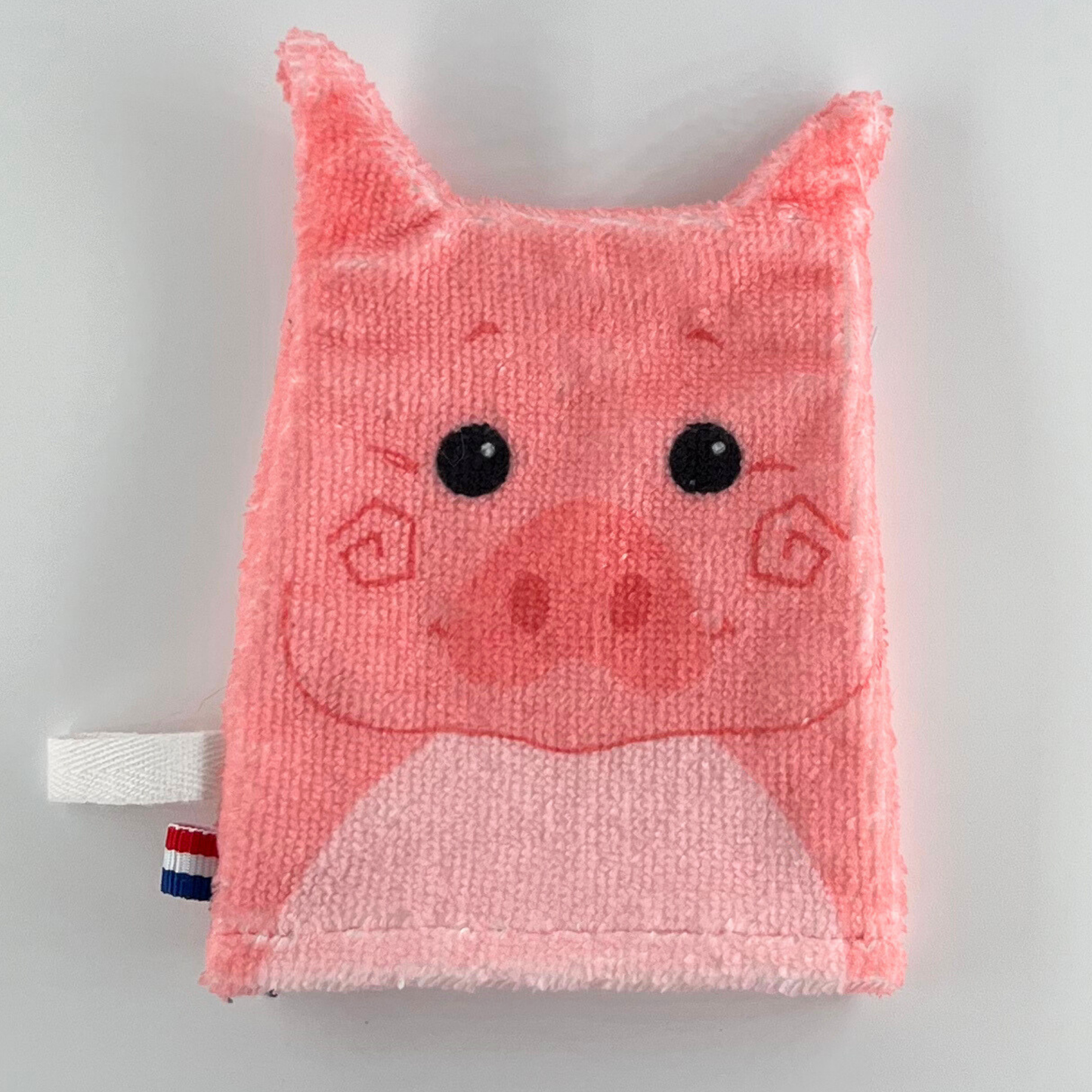 Tvättlapp i form av en rosa gris med svartvita ögon, tecknad tryckt design och små öron.