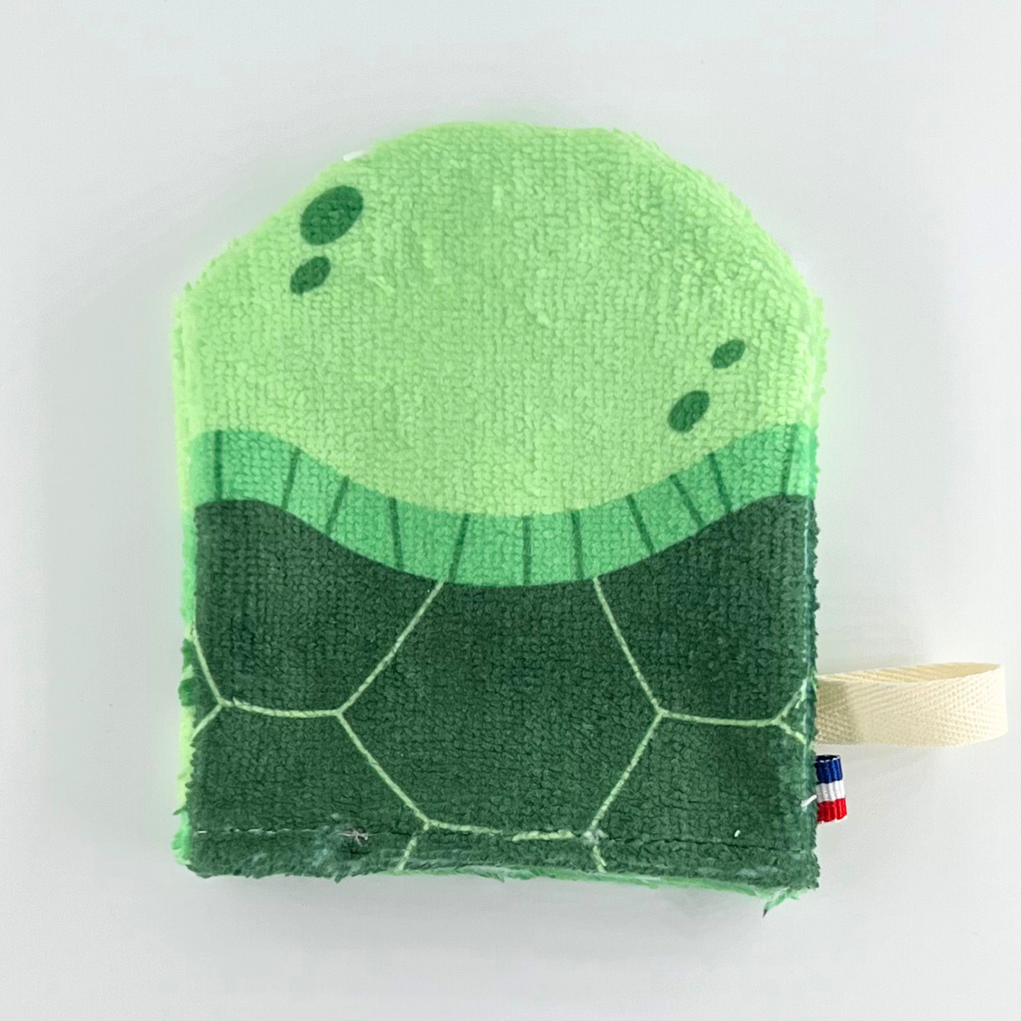 Baksidan av sköldpadda-tvättlappen med detaljerad skaldesign i olika gröna nyanser.