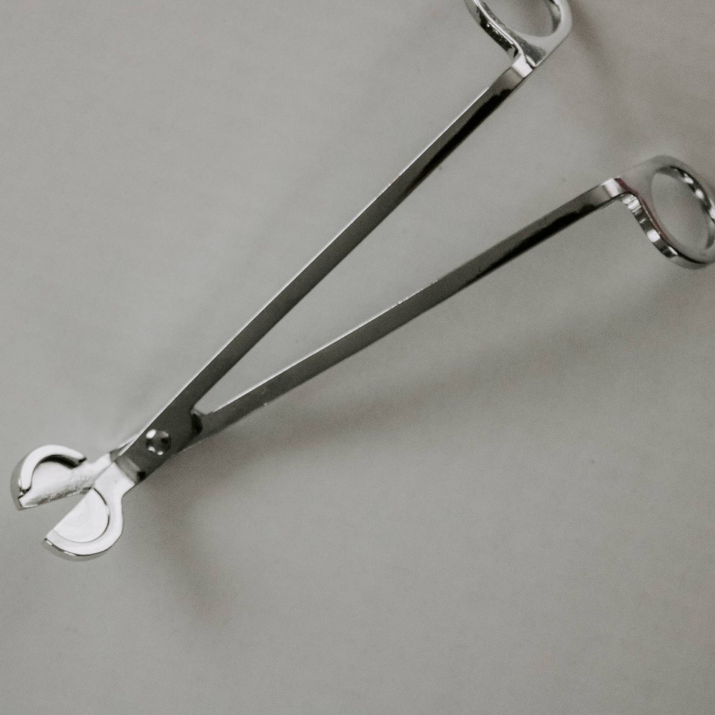 Veketrimmer i silverfärg, liggandes på vit bakgrund. Vektrimmer, veksax, ljussax, vek-trimmer.