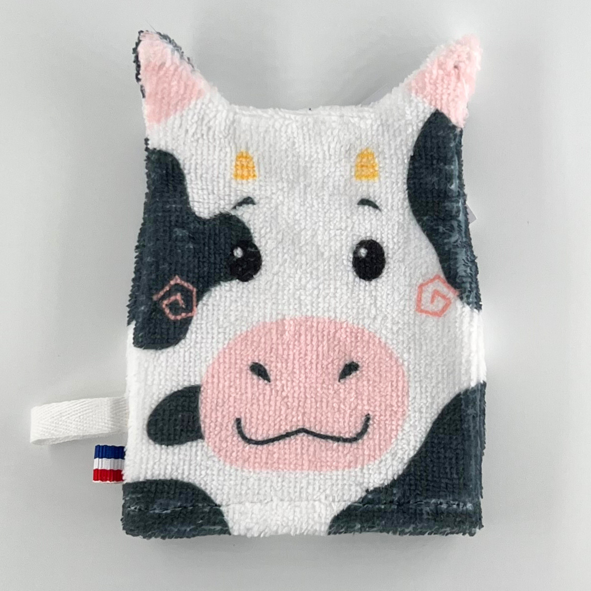 Tvättlapp som föreställer en glad ko i svart och vitt med rosa mule.